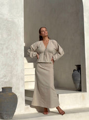 The Soli blouse, showcasing its deep, pointed neckline with subtle front ties, a gathered waist, and voluminous flowing sleeves.